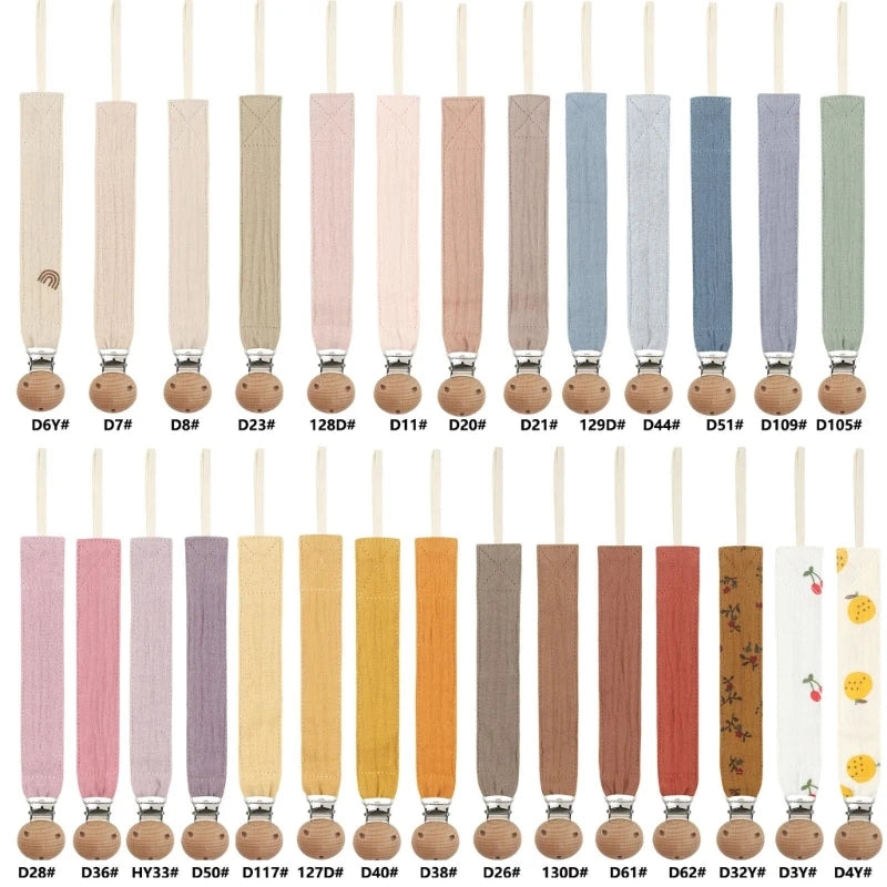 Collection d’attaches-tétine en coton aux couleurs naturelles et pastel, avec clip en bois, présentées en différentes teintes et motifs.