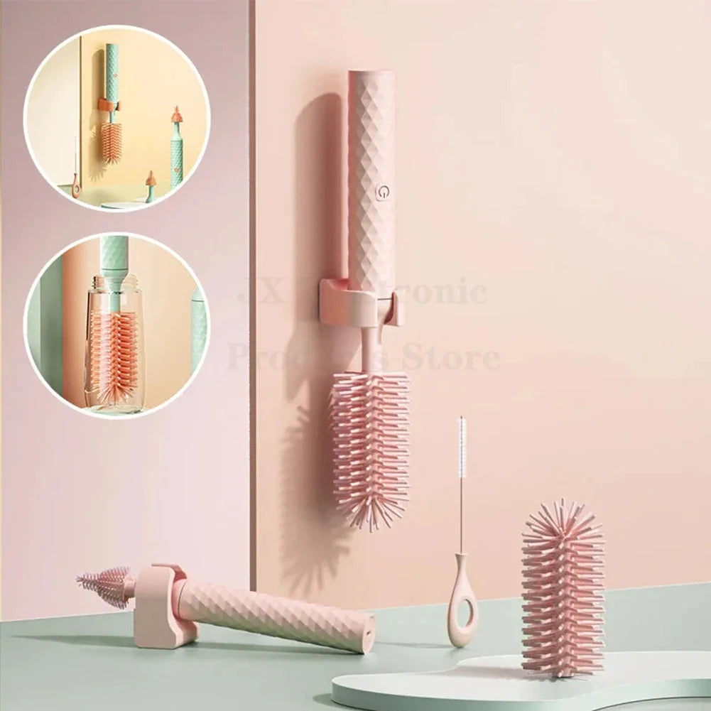 Brosse électrique en silicone pour biberons et bouteilles avec support mural, têtes interchangeables et design moderne rose pastel.