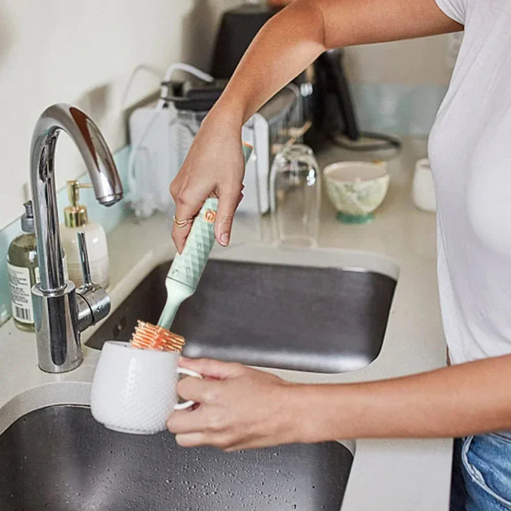 Brosse électrique en silicone utilisée pour nettoyer l’intérieur d’une tasse au niveau de l’évier de cuisine, prise en main ergonomique.