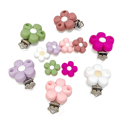 Assortiment de clips et perles en silicone en forme de fleur, coloris pastel (rose, vert, lilas, blanc, fuchsia et terracotta), pour création d’attache-tétine personnalisée.