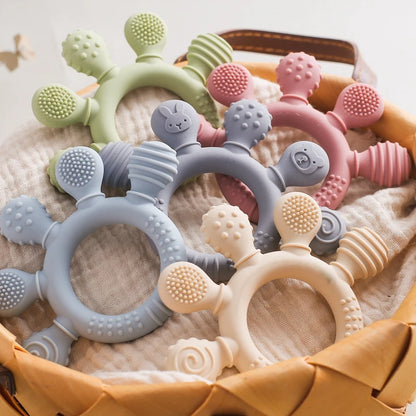 Anneaux de dentition pour bébé en silicone alimentaire, formes animales texturées, couleurs pastel, posés dans un panier