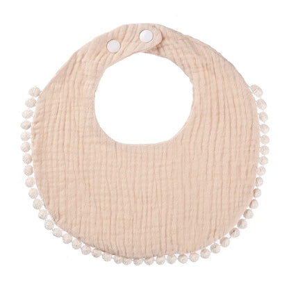 Bavoir bébé en coton mousseline beige avec bordure pompons et fermeture par boutons-pression