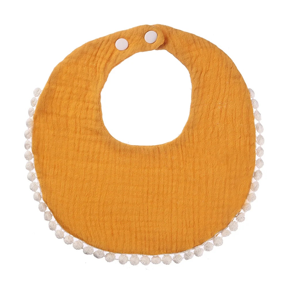 Bavoir bébé en coton mousseline jaune curcuma avec bordure pompons et fermeture par boutons-pression