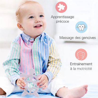 Bébé assis jouant avec un anneau de dentition en silicone, favorisant l’apprentissage précoce, le massage des gencives et la motricité