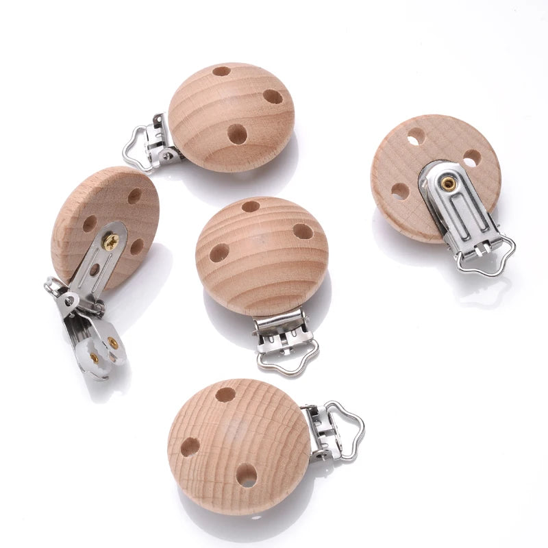 Clips attache-tétine bébé en bois de hêtre naturel ronds percés avec pince en métal, vue détaillée des trous et du mécanisme pour création de chaînes de tétine DIY