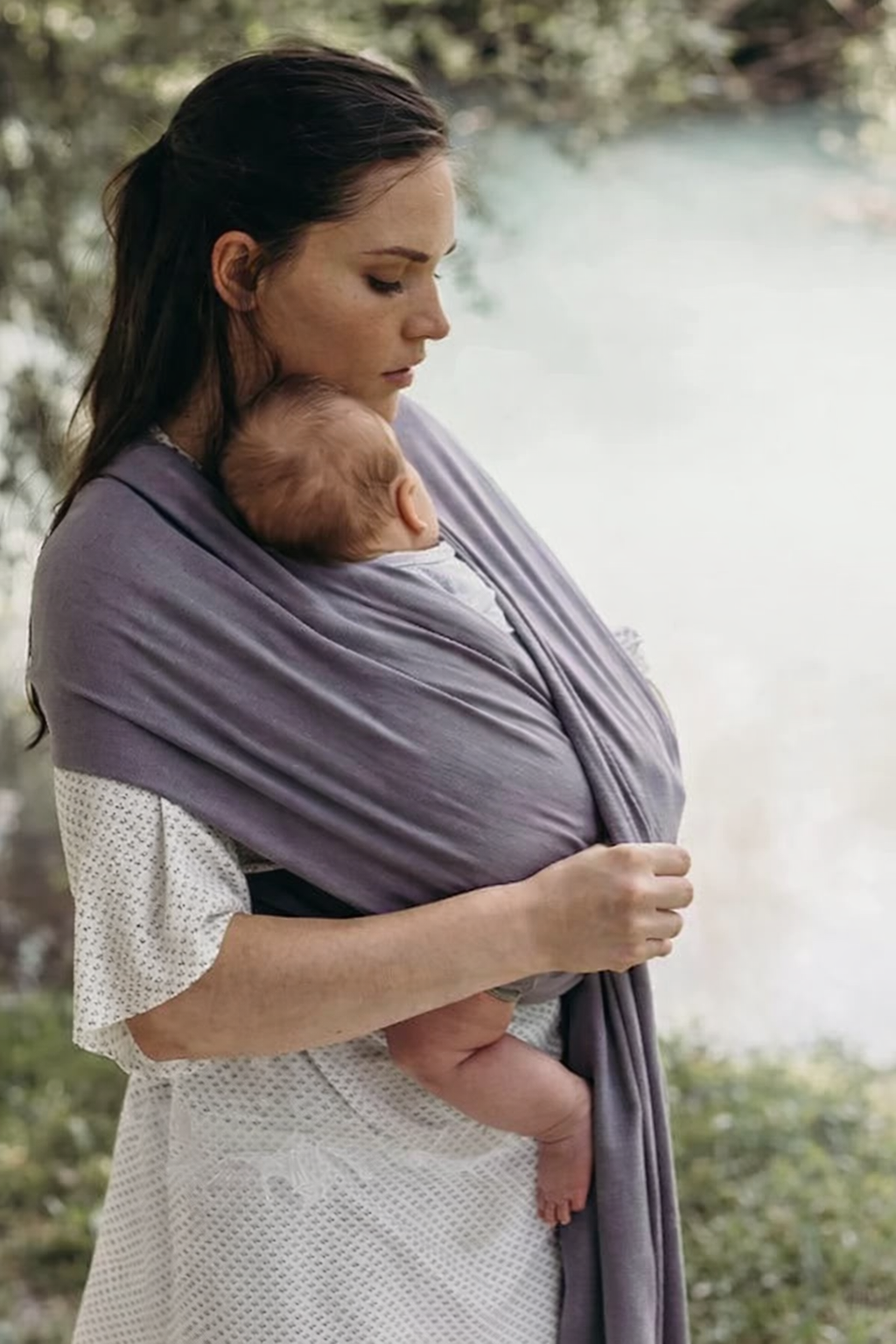 Maman portant son nouveau-né en écharpe de portage en coton extensible, offrant maintien ergonomique et proximité dès la naissance