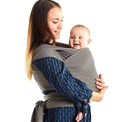 Maman portant son bébé souriant en écharpe de portage ventrale en coton extensible, assurant confort et maintien ergonomique
