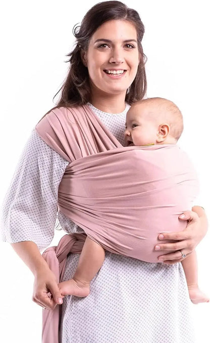 Maman portant son bébé en écharpe de portage ventrale en coton extensible rose, offrant confort et maintien ergonomique