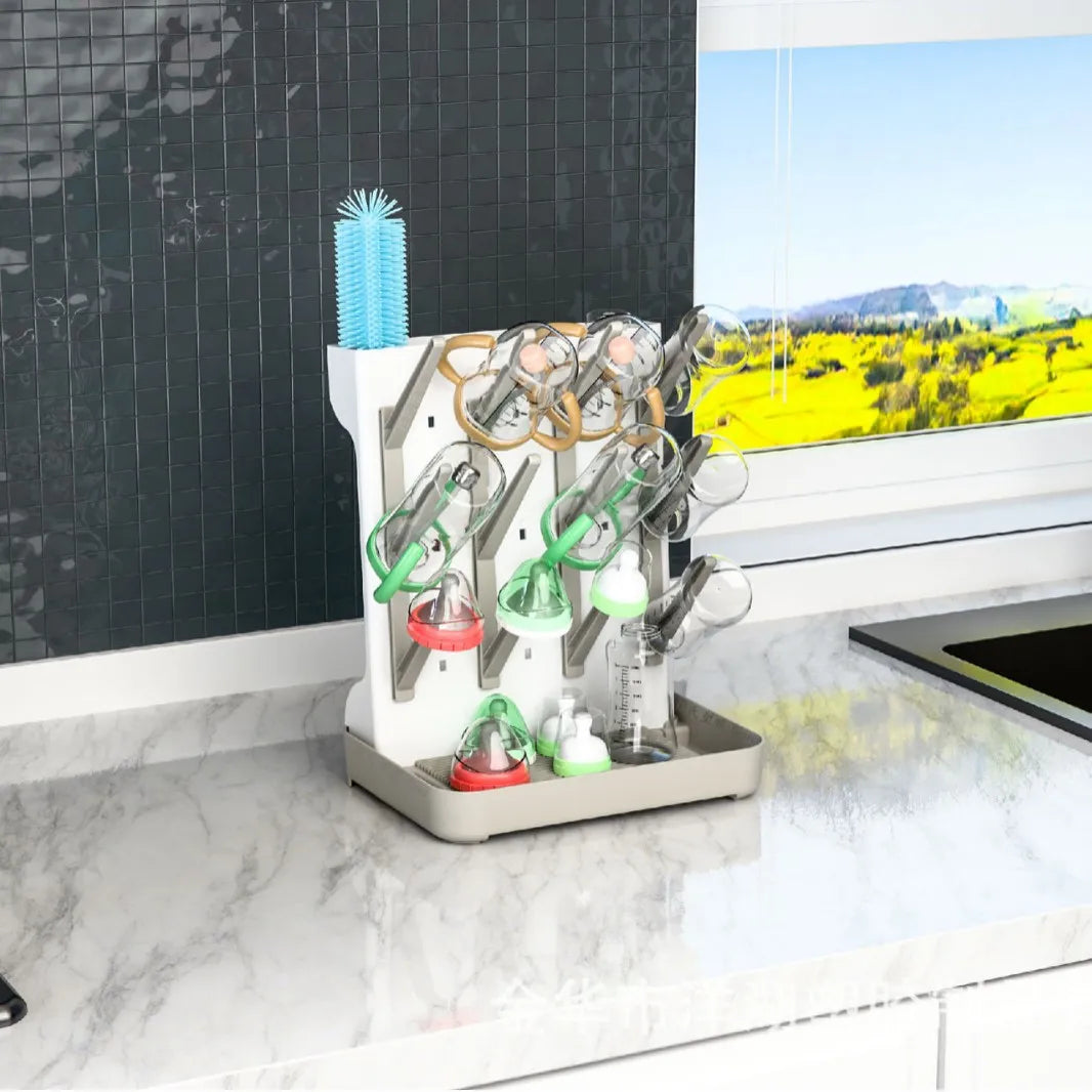 Égouttoir pour biberons bébé posé sur un plan de travail de cuisine avec biberons, tétines et accessoires en cours de séchage