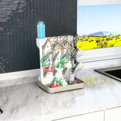 Égouttoir pour biberons bébé posé sur un plan de travail de cuisine avec biberons, tétines et accessoires en cours de séchage