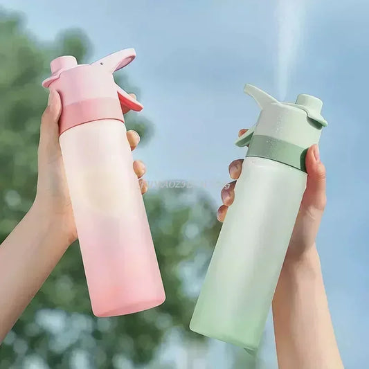 Deux gourdes spray sport 700 ml sans BPA, une rose et une verte, tenues à la main en extérieur, idéales pour le fitness, le voyage et les activités outdoor.